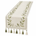 Chemin de table beige avec broderie de feuilles vertes et pompons
